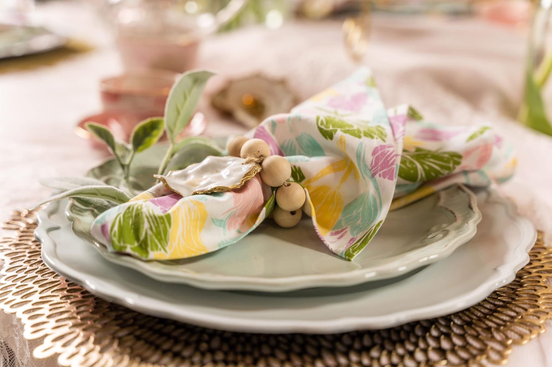 Spring place setting with floral napkin, oyster shell and beaded ring
