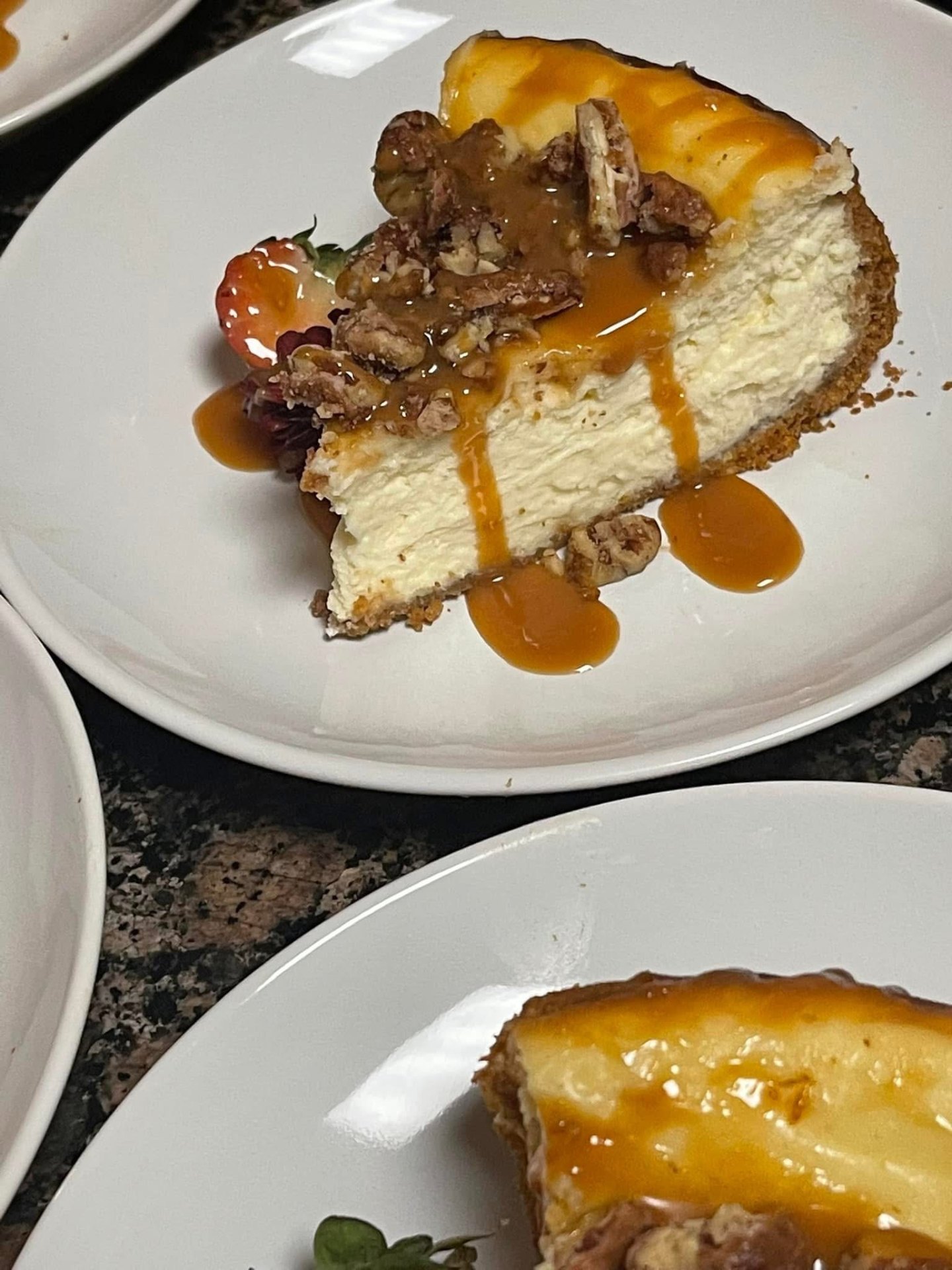 Caramel-pecan cheesecake slice plated with a fresh strawberry