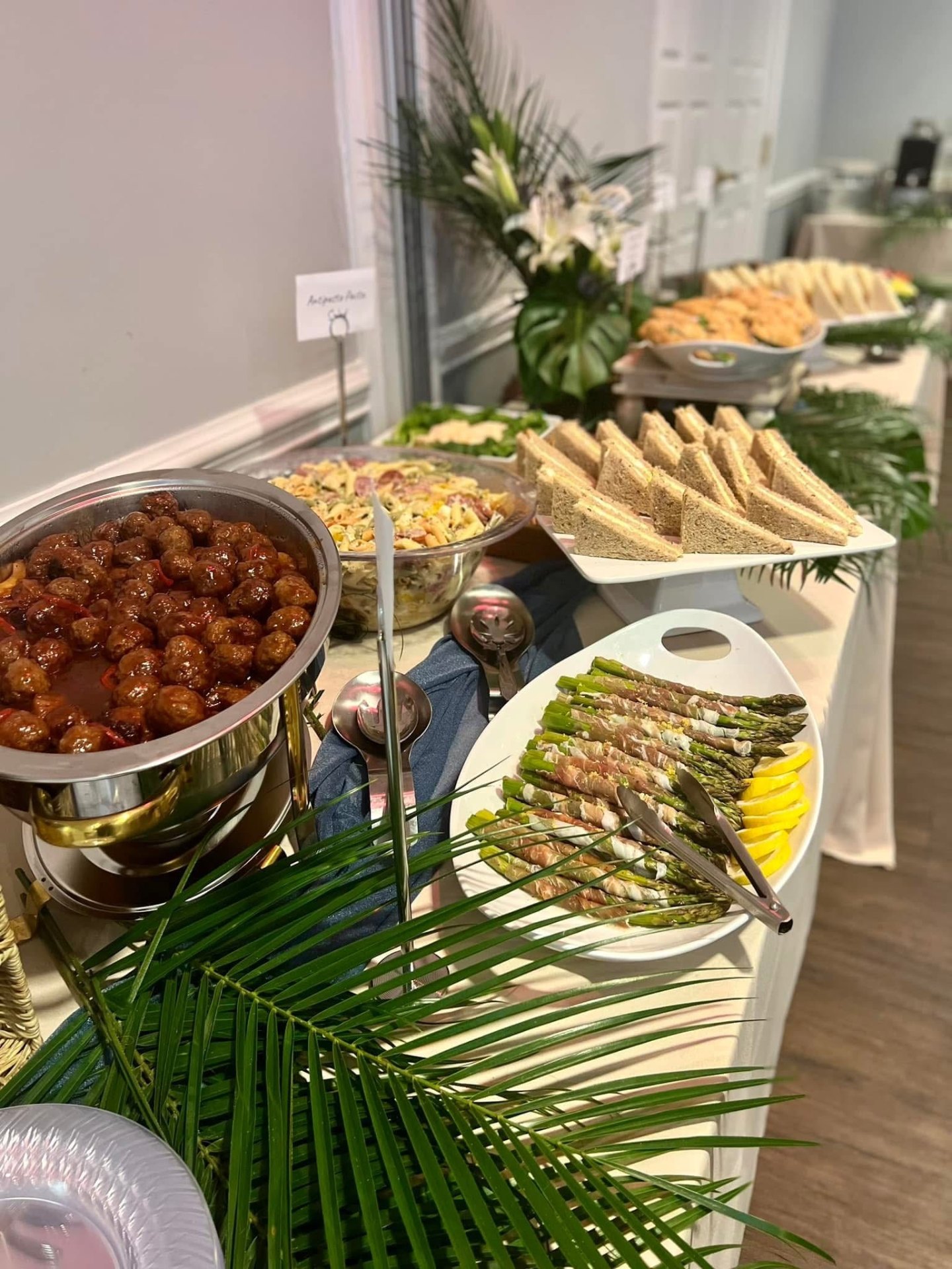 Buffet spread with glazed meatballs, pasta salad and tea sandwiches